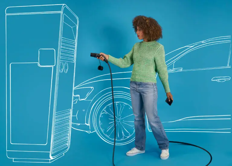 Eine Frau mit lockigem Haar steht vor einer stilisierten Ladestation für Elektroautos und hält ein Ladekabel in der Hand. Sie trägt einen grünen Pullover und Jeans, während sie ein Smartphone in der anderen Hand hält. Im Hintergrund ist die Kontur eines Autos zu sehen, was das Thema Elektromobilität unterstreicht.