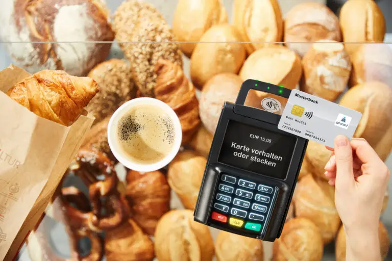 Bezahlvorgang an einem modernen Kartenterminal mit einer Kreditkarte, umgeben von frischen Brötchen, Croissants und einer Tasse Kaffee.
